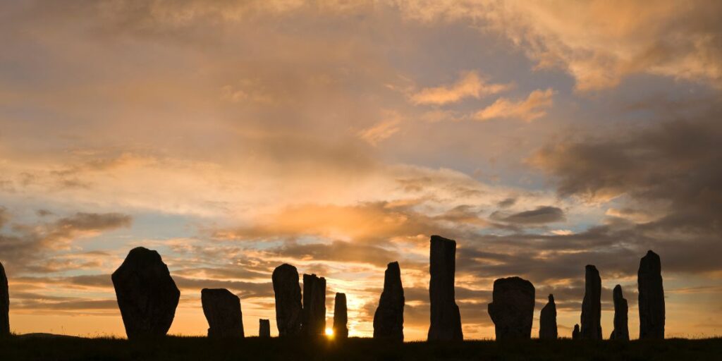 the sun rises behind a henge of sacred stones